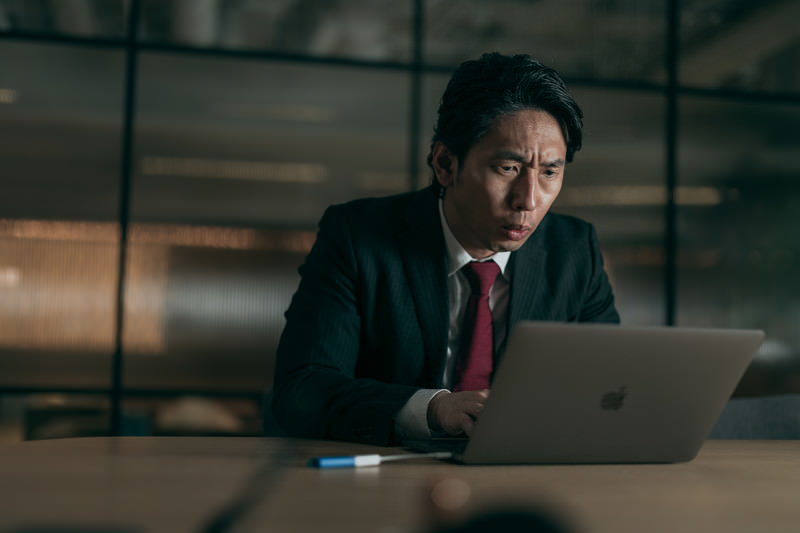 親会社からの突然のデータ要求に夜遅くまで対応する担当者